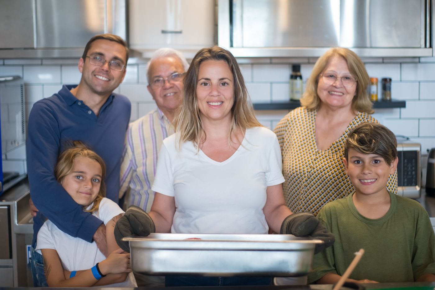 Three generations of a happy family together in their bright kitchen with stainless steel appliances