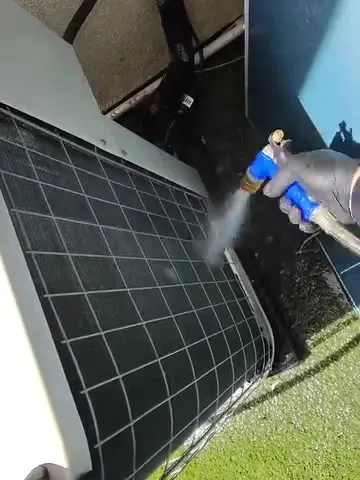 Technician cleaning an AC condenser coil